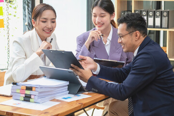 Asian business team consists of marketing staff. accountant and financial officer Help each other analyze company profits using tablets. calculator Laptop computers, graph paper, and corporate pens.