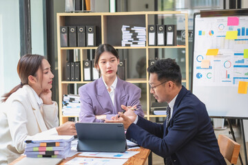 Asian business team consists of marketing staff. accountant and financial officer Help each other analyze company profits using tablets. calculator Laptop computers, graph paper, and corporate pens.