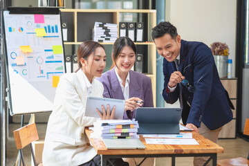 Asian business team consists of marketing staff. accountant and financial officer Help each other analyze company profits using tablets. calculator Laptop computers, graph paper, and corporate pens.