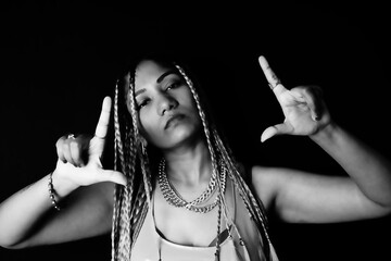 Female rapper gesturing over black background - obrazy, fototapety, plakaty