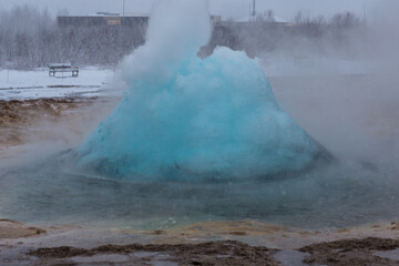 Geyser in fase iniziale di eruzione mentre si sta creando la bolla azzurra durante una nevicata