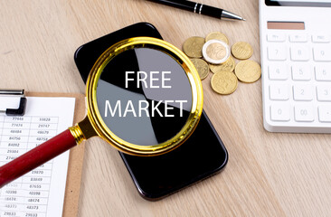 FREE MARKET text on the magnifier with smartphone, calculator and coins