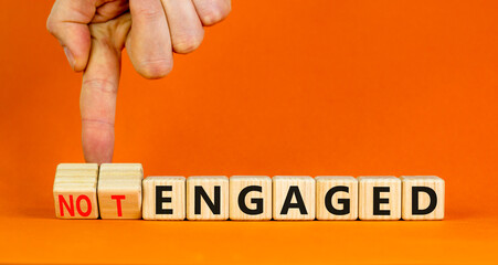 Engaged or not symbol. Concept words Engaged and Not engaged on wooden cubes. Businessman hand. Beautiful orange table orange background. Business engaged or not engaged concept. Copy space.
