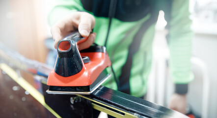 Process applying wax with hot iron on ski cross country in workshop repairman