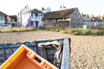 Fototapeta na wymiar Shallow focus of an orange, plastic crate seen discarded in a on wooden boat. Located on the Suffolk coast.