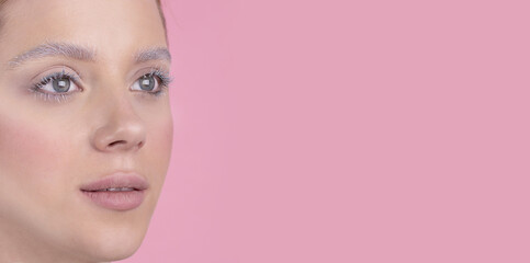 Fototapeta premium A girl with blue eyes and winter make-up, snowy eyelashes and eyebrows. Artistic close up photo Pink backround .Space for text on the right Fashion, beauty, makeup, cosmetics, beauty salon, style