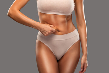 Girl pulls the skin on the abdomen, showing the body fat. Treatment and disposal of excess weight, the deposition of subcutaneous fat.