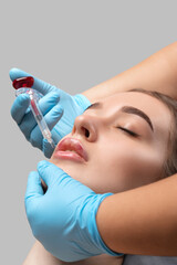Cosmetologist does injections for lips augmentation anti wrinkle injections on the face of a...