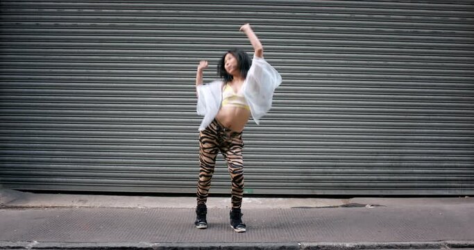 Dance, city and freedom with an asian woman dancing against a steel gate with mockup for fun. Music, street and fashion with an attractive young female moving outdoor in an urban town with energy