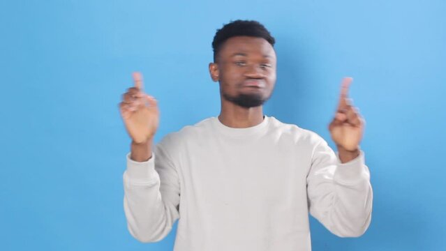 A young African American he gestures for Noor to stop, arms crossed shaking his head saying no. Posing on a blue studio background Close-up.