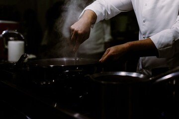 A cook stirring pots in the kitchen. Big pots in the kitchen.
BLURRY BACKROUND. BLURRED