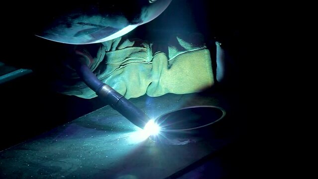 The worker welds steel parts with a semi-automatic welding machine