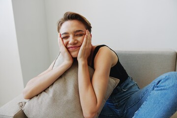 Young woman with short haircut hair having fun at home on the couch smile and happiness, vacation at home, natural posing without filters, free copy space