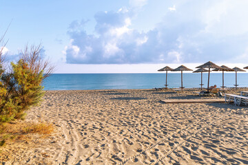 Fototapeta premium Empty beach with sun loungers and umbrellas in the early morning on a sunny day on the Crete island Greece. . High quality photo
