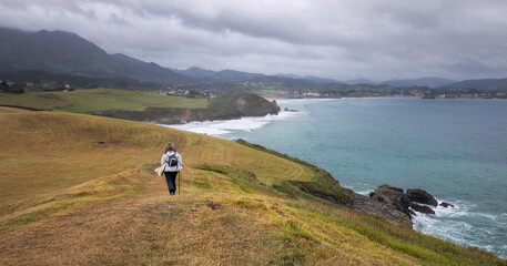 Fototapeta na wymiar Woman Hiking a Coastal Path to Arenal de Moris Beach in Asturias, Spain