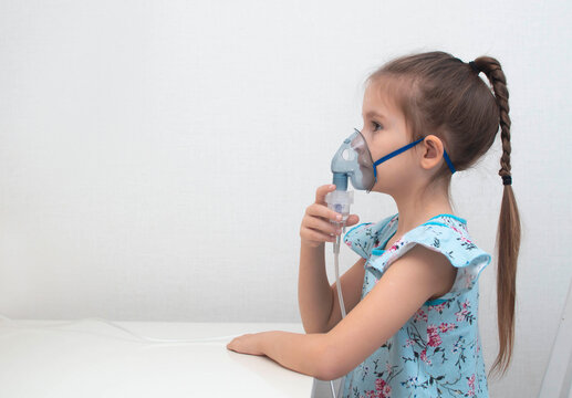 girl is holding an inhaler and breathing. He was filmed for articles about diseases of upper respiratory tract, respiratory diseases, colds and pneumonia. Child does inhalation with nebulizer.