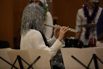 A person decorated with tinsel plays a flute during the training of the orchestra of the Christmas...
