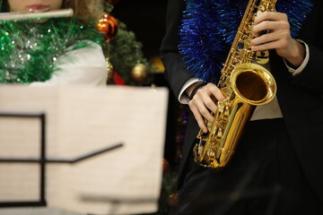 Fototapeta premium Person with Christmas decorations playing the golden saxophone in the orchestra at a holiday concert