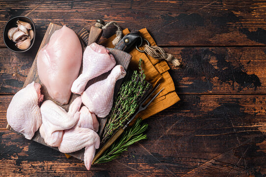 Assortment of chicken portions for Bbq grilling. Raw parts - drumstick, breast fillet, wings, thigh. Wooden background. Top view. Copy space