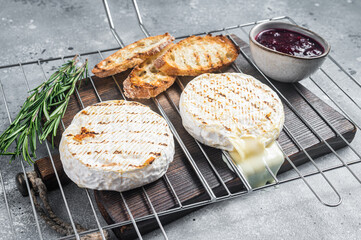 Grilled Camembert cheese on grill with cranberry sauce and toast. Gray background. Top view