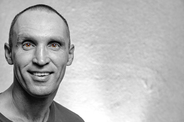 Close-up of his portrait, he is a nice attractive funny smiling adult man in a black and white portrait, with colored eyes