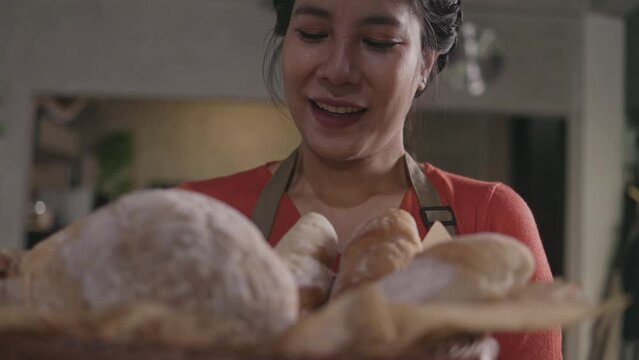 Asian baker smelling fresh baked bread taken out of oven at moment