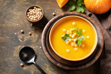 Vegetarian pumpkin and chickpea cream soup on a rustic wooden table. Comfort food, fall and winter...