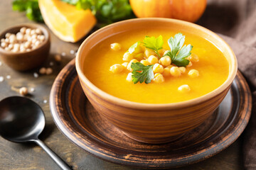 Vegetarian pumpkin and chickpea cream soup on a rustic wooden table. Comfort food, fall and winter healthy slow food concept.