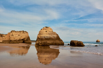 Symmetrical reflection of the limestone rocks in the water of low tide. Praia dos Tres Castelos, Portimao