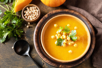 Comfort food, fall and winter healthy slow food concept. Vegetarian pumpkin and chickpea cream soup on a rustic wooden table.