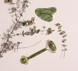Jade green face massager on a beige background, top view