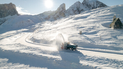 Snow Plow Truck is cleaning the road and blowing snow away in the Dolomites. Sun is shining over...