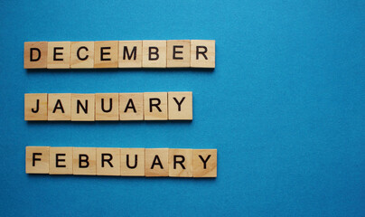 Wooden calendar of winter months December January February. Of turf cubes on a blue background. Flat styling style. Top view