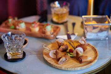 Plate with snacks and glass of alcoholic drink on table in bar or restaurant