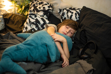 Obraz premium the boy fell asleep hugging the shark. the child lies in his bed on a pillow, with black and white linens