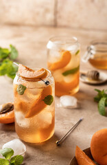 Fresh apricot cocktail, fizz or ice tea with mint and garnish. Pink beige tile background