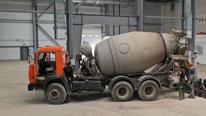 Pouring concrete mortar from a concrete mixer inside a huge production hangar. Filling the...