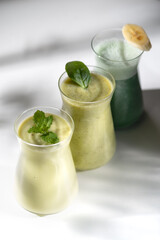 Freshly blended fruit smoothies of various colors and tastes in glass jars. Yellow green.