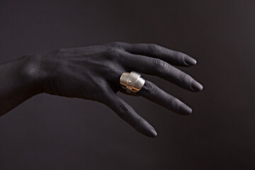 Black woman's hand with Silver jewellery. Oriental Bracelets on a black painted hand. Silver Jewelry and luxury accessories on black background closeup.