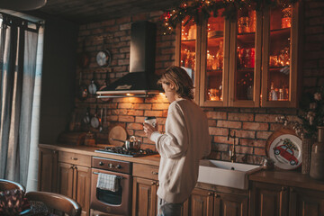Fototapeta na wymiar Portrait of candid authentic boy teenager holiday cooking in kitchen at wooden lodge Xmas decorated