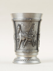 Traditional German vintage pewter wine glass with a bas-relief depicting a man in a hat on a horse-drawn carriage