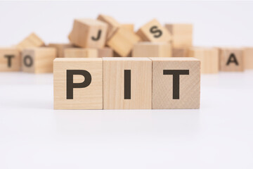 text PIT - personal income tax - is written on three wooden cubes standing on a white table. in the...
