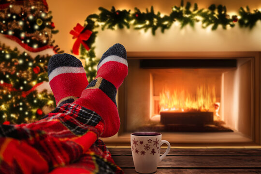 Christmas holiday mood relaxing in front of cozy fireplace and enjoying cup of hot chocolate