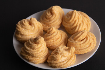 photo of several large meringues lying on a plate in close-up on a black background