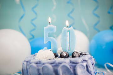 Happy fiftieth birthday navy cake and number fifty candle with blue balloons and decoration