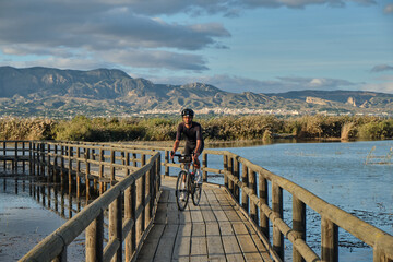 male cyclist rides a bicycle on a wooden bridge over a river