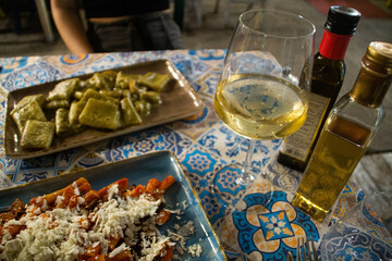 Dinner at outdoor restaurant - pasta alla Norma, pasta with pistachio sauce and wine glasses