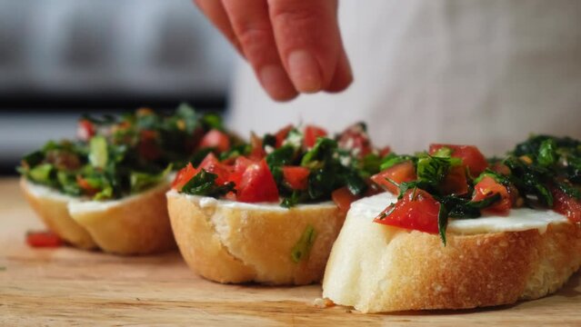 Person spreading cream cheese on piece of baguette bread. Spreading cream cheese on bread. Smear soft cheese on bread. chef makes delicious bruschetta. delicious bruschetta with tomatoes and eggs