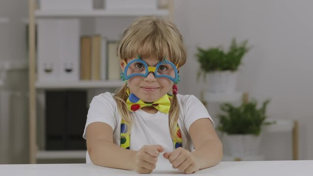 Funny girl of 7 years dressed in clown eye glasses, butterfly and suspenders.