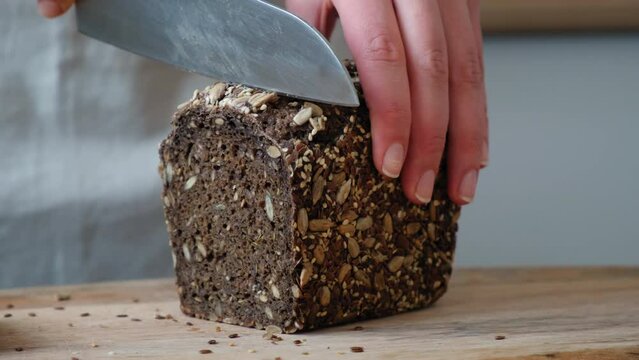 the cook cuts grain rye bread and spreads it with selected butter. Slicing whole wheat bread on cutting board. Smear organic butter on bread. Soft butter spreading on slice of sourdough bread.